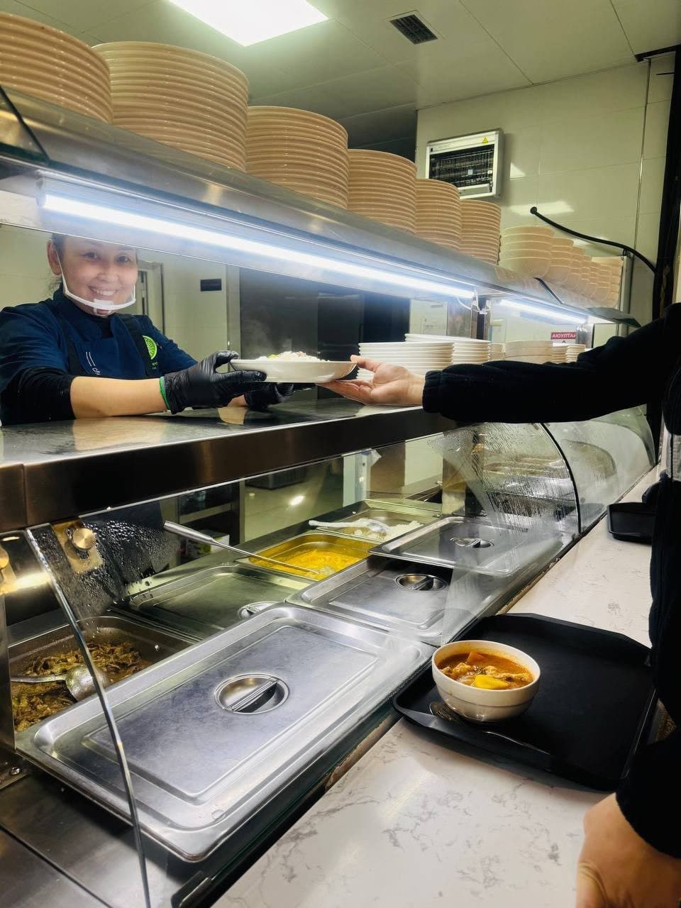 A cook serving a plate through the counter